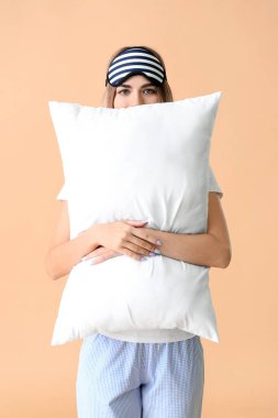 Pijamalı genç bir kadının portresi. Arka planda uyku maskesi ve yastığı var.