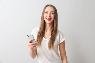 Arka planda cep telefonu olan genç bir kadın.