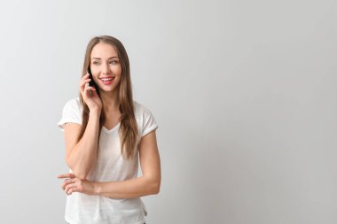 Genç bayan arka planda cep telefonuyla konuşuyor.