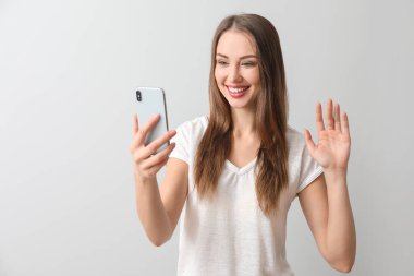 Arka planda cep telefonu olan genç bir kadın.