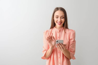 Arka planda cep telefonu olan genç bir kadın.