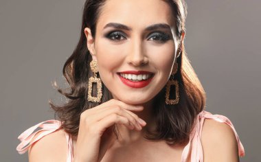 Gri arka planda güzel makyajlı genç bir kadın.