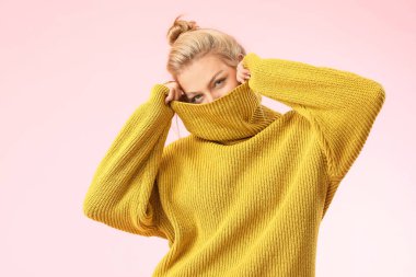 Renkli arka planda kalın kazaklı genç bir kadın.