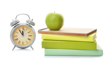 Okul kitapları, beyaz arka planda elma ve saat. Çalışma zamanı.