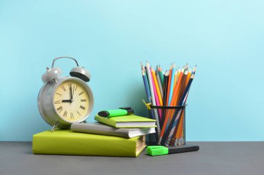 Okul malzemeleri ve saat seti masanın üzerinde. Çalışma zamanı.
