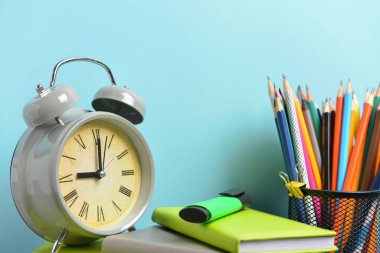 Okul malzemeleri ve saat seti masanın üzerinde. Çalışma zamanı.