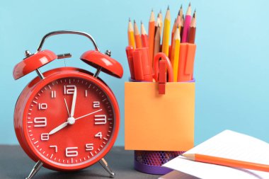Okul malzemeleri ve saat seti masanın üzerinde. Çalışma zamanı.