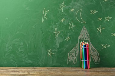 Okul tahtasının yanındaki masada çizilmiş roketli kalemler.