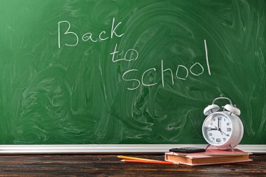 Okul malzemeleri ve saat seti masanın üzerinde. Çalışma zamanı.