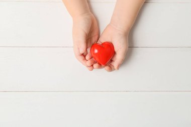 Ahşap arka planda kırmızı kalpli çocuk elleri. Kardiyoloji kavramı