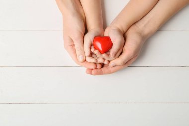 Ahşap arka planda kırmızı kalpli kadın ve çocuğun elleri. Kardiyoloji kavramı