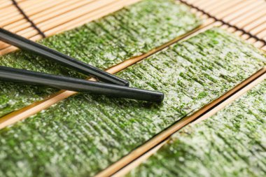 Lezzetli yosun çarşafları ve bambu hasırı üzerinde çubuklar, yakın plan.