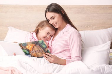 Anne ve küçük kızı evde yatmadan önce hikaye okuyor