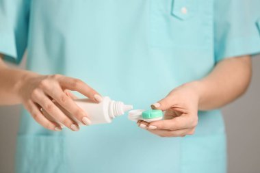 Kadın konteynıra kontak lensli solüsyon dolduruyor, yakın plan.