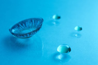 Renk arkaplanına kontak lens ve su damlaları