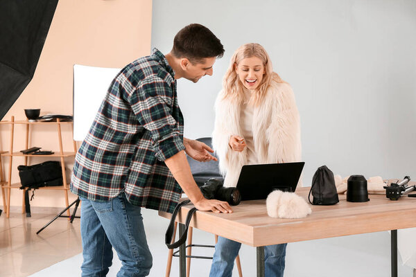 Professional photographer showing pictures to model in studio