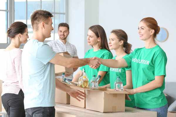 Team of volunteers giving products to poor people