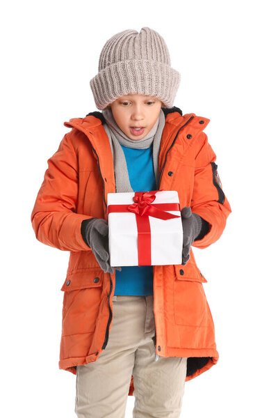 Удивленный мальчик в зимней одежде и с подарком на белом фоне
