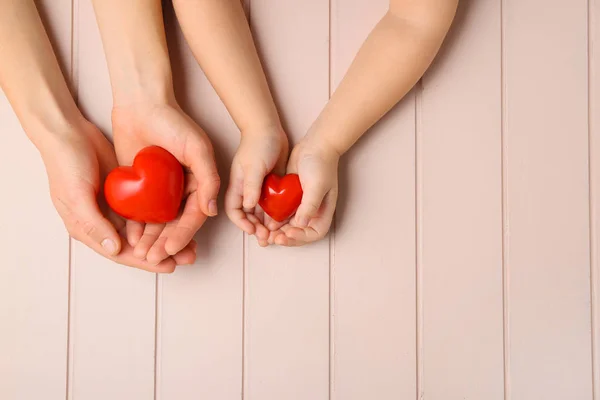 木製の背景に赤い心を持つ女性と子供の手 心臓病の概念 — ストック写真