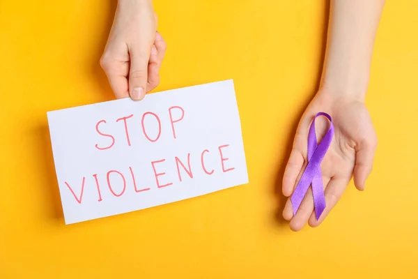 紫色のリボンとテキスト付きの紙と女性の手色の背景に暴力を停止 — ストック写真