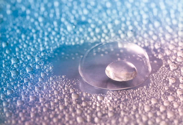 Contact lens and water drops on color background