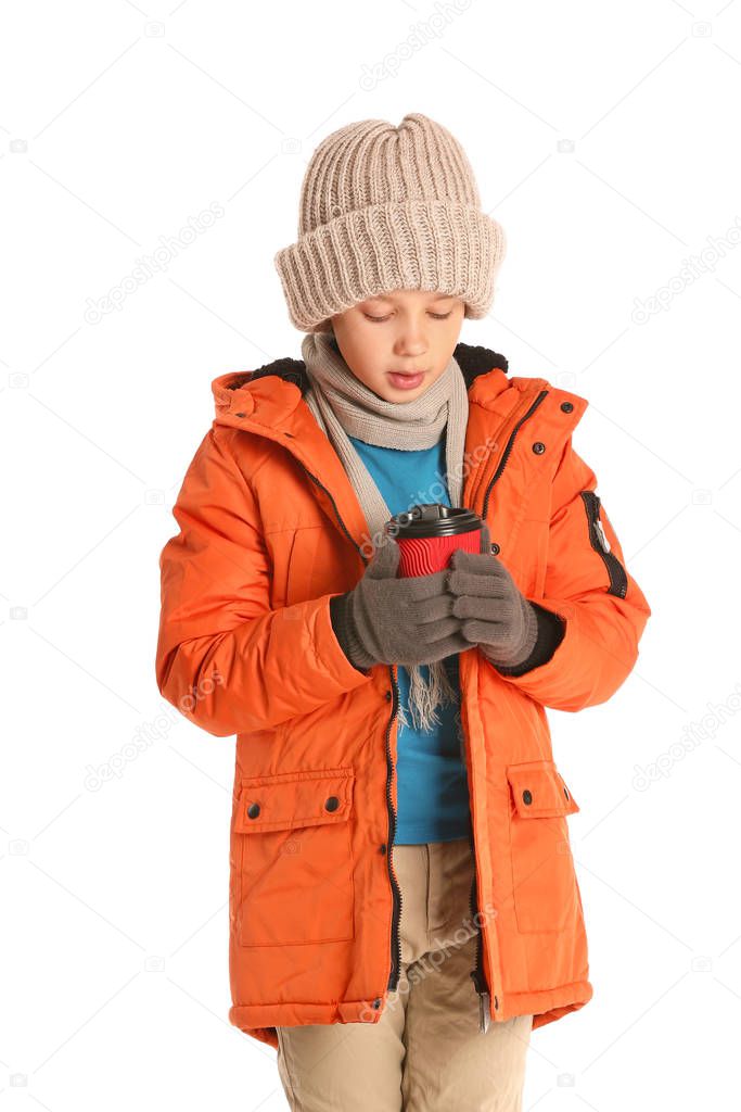 Cute little boy in winter clothes and with cup of hot chocolate on white background