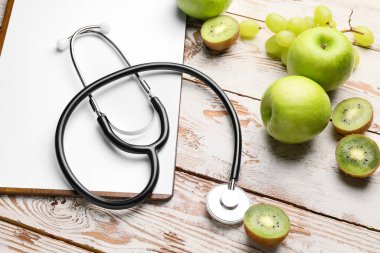 Sağlıklı ürünleri olan bir pano ve beyaz ahşap arka planda steteskop