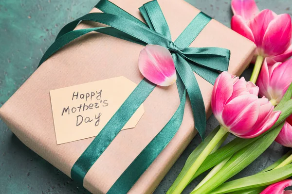Beautiful flowers and gift for Mother's Day on color background