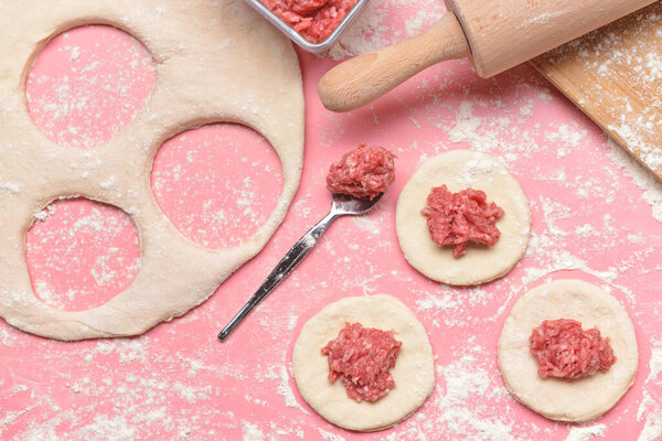 Изготовление вкусных пельменей на цветном фоне
