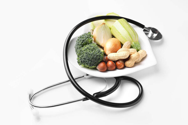 Тарелка со здоровыми продуктами и стетоскопом на белом фоне
