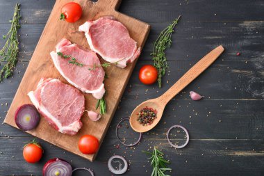 Koyu ahşap arka planda çiğ domuz eti, sebze ve baharatlı pano.