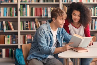 Kütüphanede sınava hazırlanırken kitap okuyan genç öğrenciler