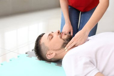 Eğitmen ilk yardım kursunda adama kalp masajı yapıyor.