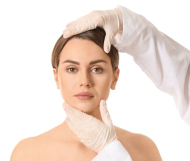 Plastik cerrah beyaz arka plan üzerinde genç kadının yüzüne dokunmadan