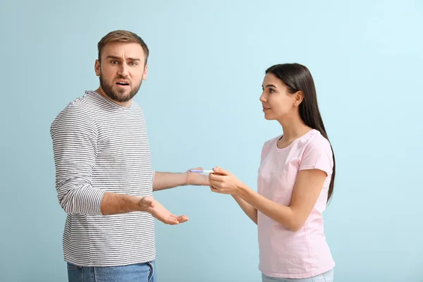 色の背景に妊娠テストを持つ感情的な若いカップル — ストック写真