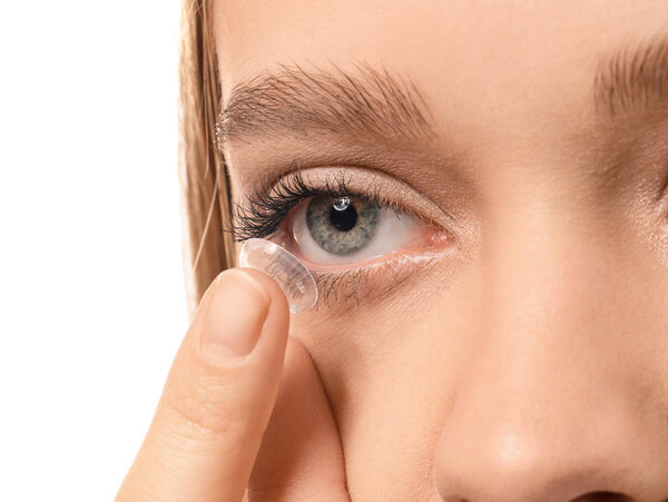 Young woman putting in contact lens on white background, closeup