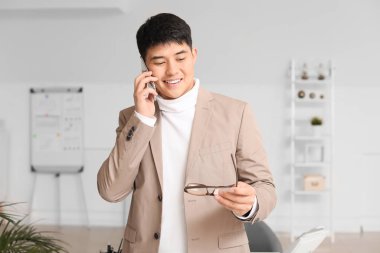 Young Asian businessman talking by phone in office
