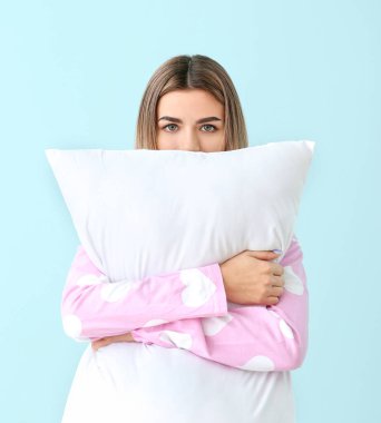 Pijamalı ve arka planında yastık olan genç bir kadının portresi.