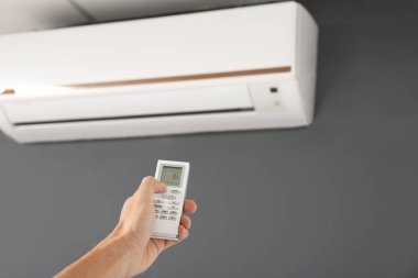 Uzaktan kumandalı erkek teknisyen içerideki klimayı kontrol ediyor.