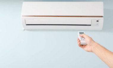 Uzaktan kumandalı erkek teknisyen içerideki klimayı kontrol ediyor.