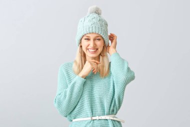 Gri arka planda kalın kazaklı güzel bir kadın.