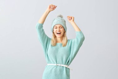 Gri arka planda sıcak süveter giyen güzel, mutlu bir kadın.