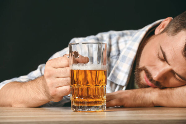 Пьяный человек с пивом за столом. Концепция алкоголизма
