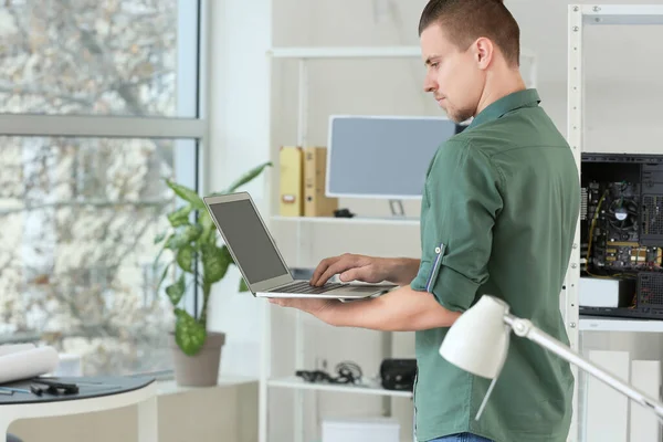 Electronic technician with laptop in service center