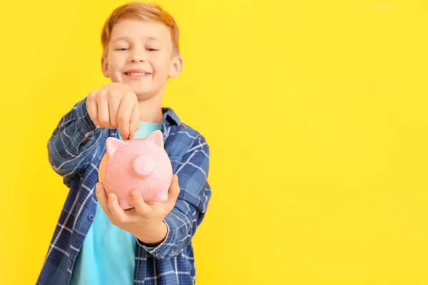 Cute Boy Putting Money Piggy Bank Color Background — Stock Photo, Image