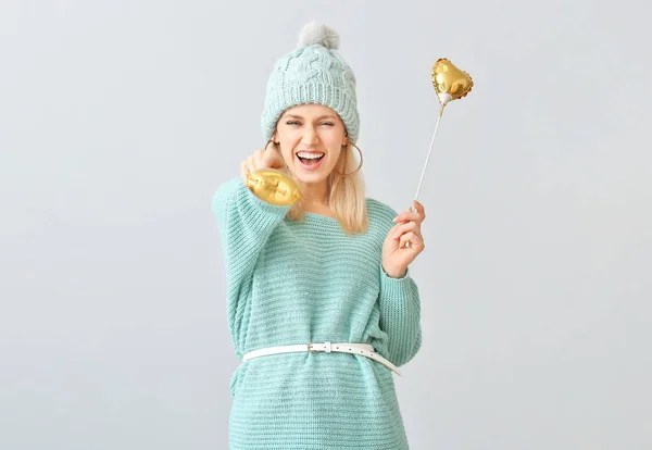 暖かいセーターの美しい若い女性とグレーの背景にパーティーの装飾 — ストック写真