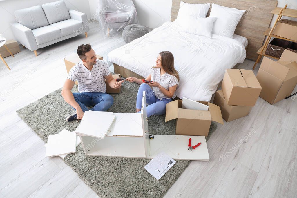 Young couple assembling furniture at home