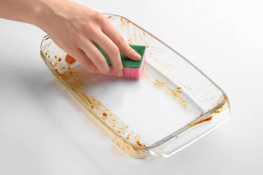 Woman cleaning baking dish on white background clipart