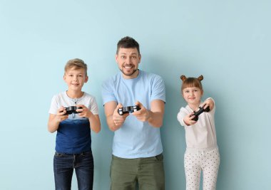 Baba ve küçük çocukları renkli arka planda video oyunu oynuyorlar.