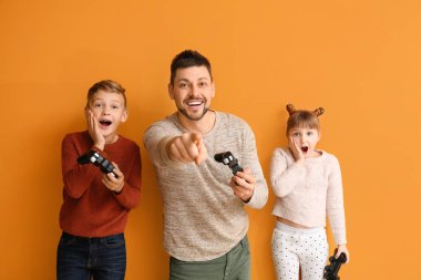 Baba ve küçük çocukları renkli arka planda video oyunu oynuyorlar.